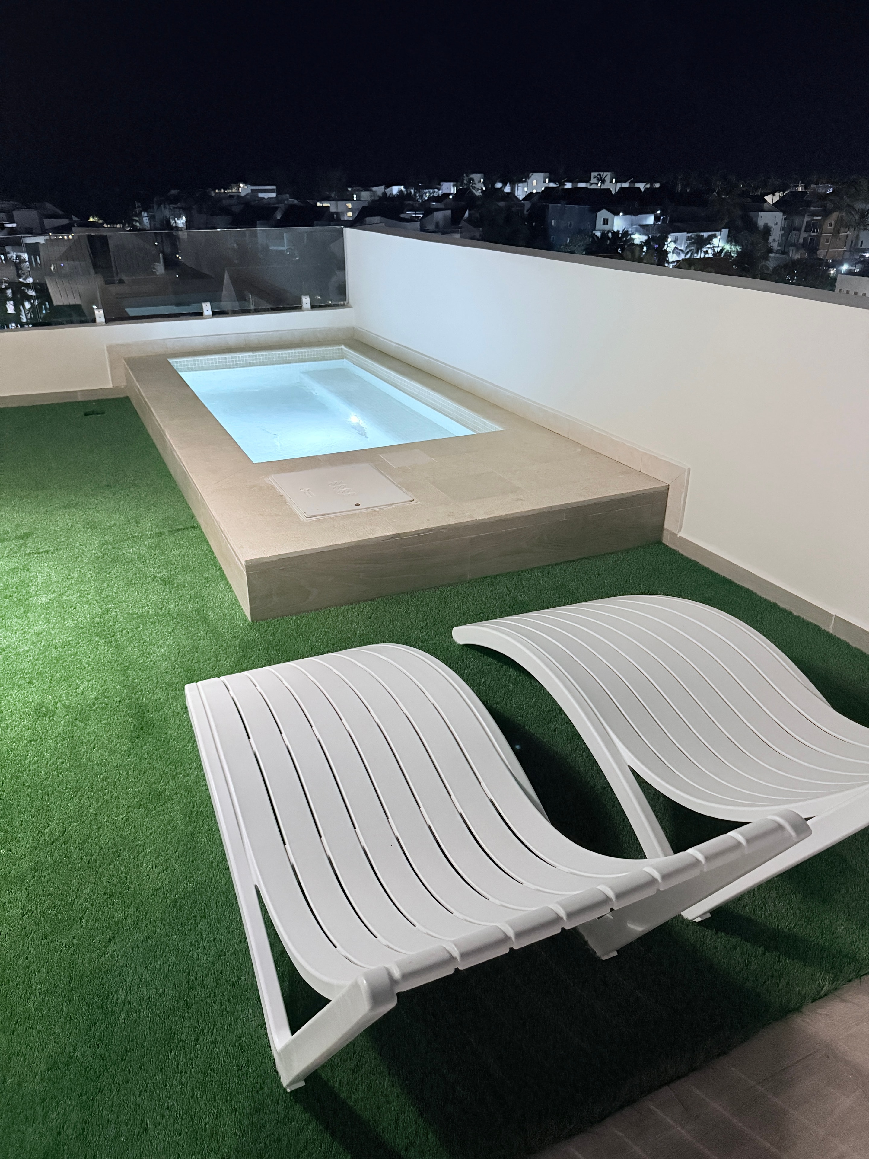 AlaNiqueStay rooftop pool deck with lounge chairs at night